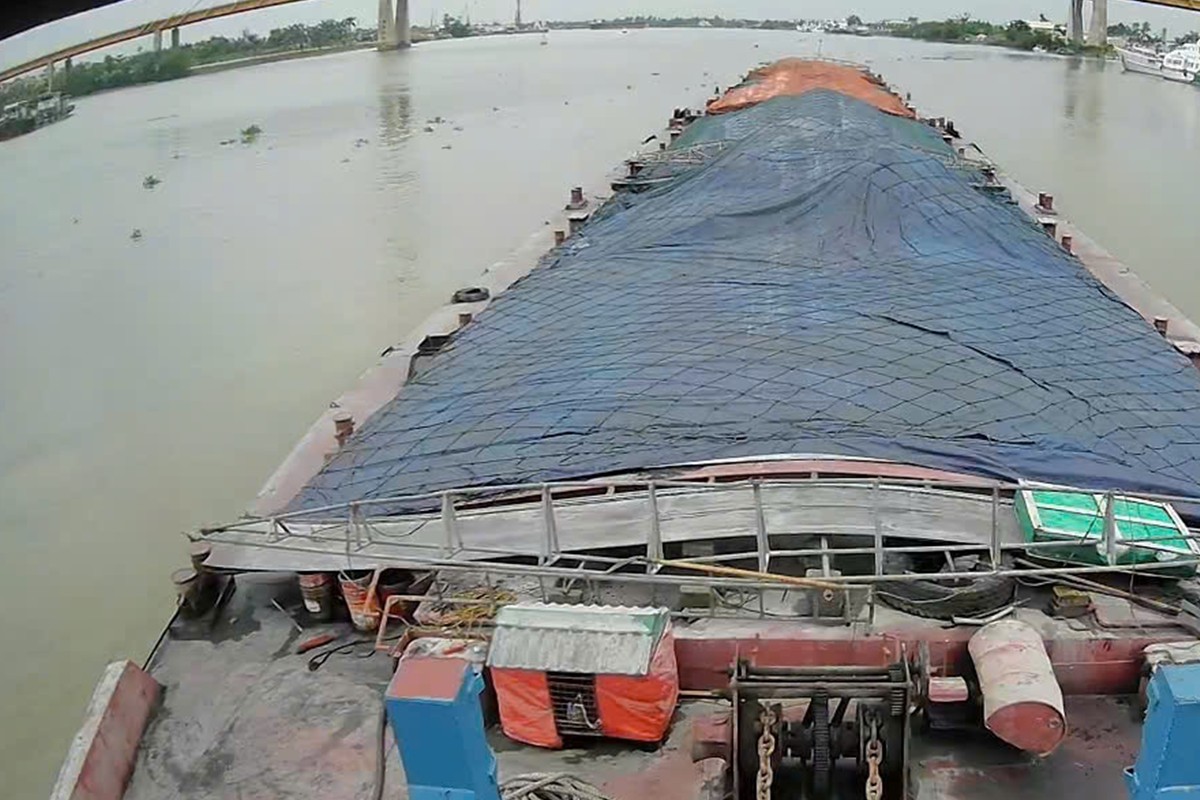 Barge with tarpaulin-covered cargo on the river